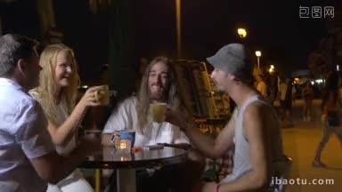 一群兴高采烈的朋友晚上坐在街边的咖啡馆里碰杯